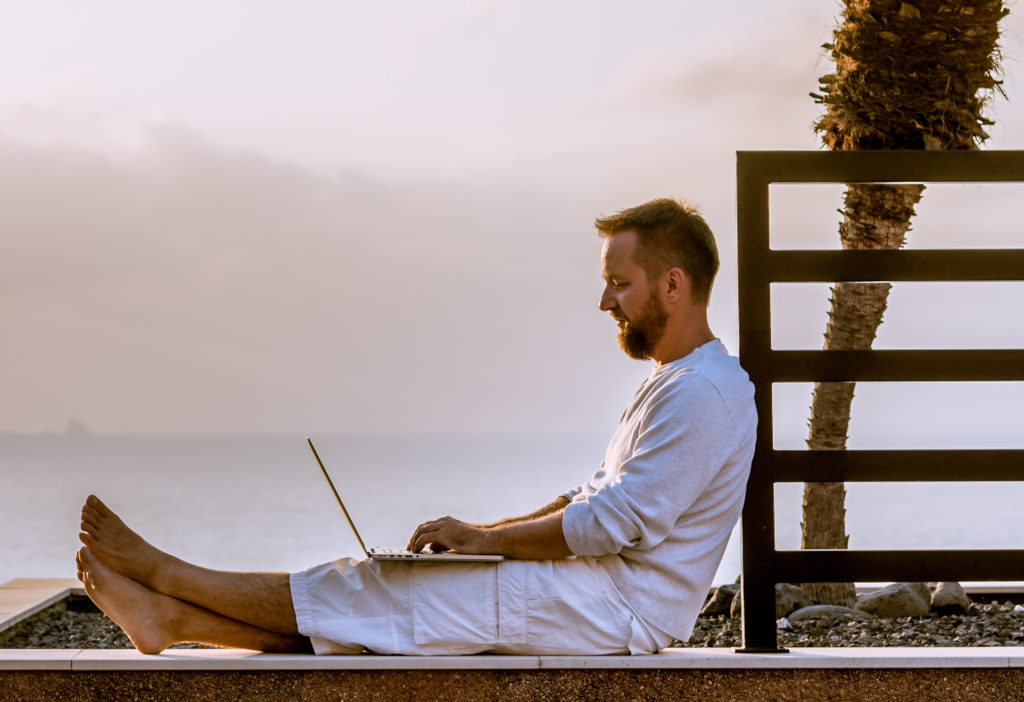 Young man with laptop working at sunset