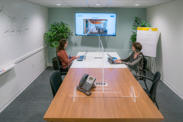 two people in meeting room with dividers between them